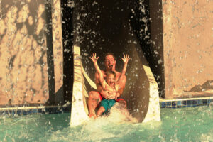 Father son sliding down water slide